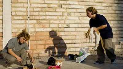 Ghina and Hana Saemeldahr feed stray cats outside a mosque near the Corniche in Abu Dhabi.