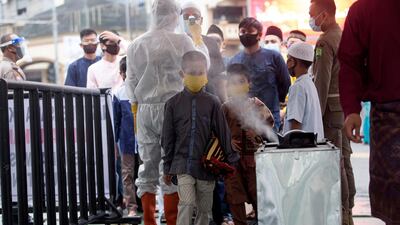 A boy walks past a disinfectant sprayer at the Al Mashun Grand Mosque to attend prayers in Medan, North Sumatra, Indonesia. AP Photo