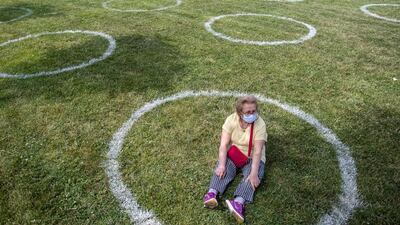 A woman wearing mask sits in a circle marked by the municipality to observe social distancing at the Maltepe Orhangazi city park in Istanbul. EPA