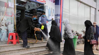 A worker disinfects the feet of women as a preventive measure against the spread of the new coronavirus before they enter a mall in Sanaa, Yemen. AP
