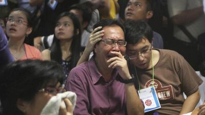 Relatives of passengers of the missing AirAsia flight react upon seeing the news on television about the findings of bodies near the site where the jetliner disappeared. This photo was taken at the crisis centre at Juanda International Airport in Surabaya, East Java, on December 30, 2014. Trisnadi/AP Photo