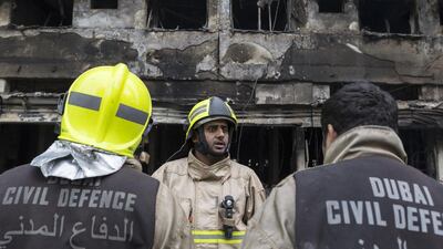 Civil Defence team work to clean the burnt apartment building in Deira.