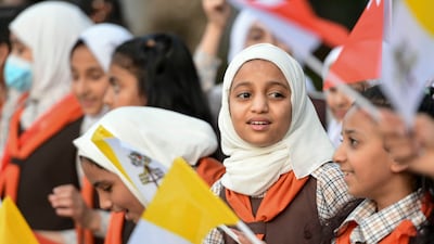 Schoolchildren wave flags to welcome the pontiff. Khushnum Bhandari / The National