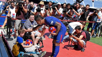 Barcelona's new Brazilian midfielder Paulinho gives a ball to a child in a wheelchair. Lluis Gene / AFP