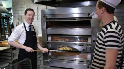 Chancellor of the Exchequer George Osborne takes a pizza he made from the oven as a staff member looks on during a visit to a Pizza Express restaurant in 2015 in Hove. Getty Images