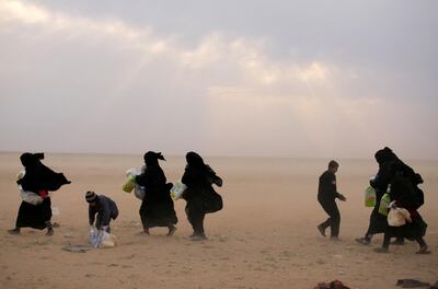 Women walk with their belongings near the village of Baghouz in Deir Ezzor. Reuters