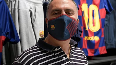 A supporter poses wearing a mask bearing the logo of FC Barcelona after buying it at the FC Barcelona store. AFP