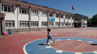 A child wearing a face mask runs at the school playground at Cankaya primary school, on August 18, 2020, in Ankara. AFP