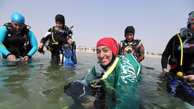 Abrar Abu Abdullah, a Saudi female diver smiles as she wears Saudi national flag over her shoulders as she enters the sea to dive at Half Moon Beach open-water dive site in Dhahran, Saudi Arabia. Reuters
