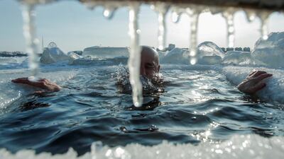 An enthusiast of winter swimming takes a dip in icy water, with buildings of Chinese border city Heihe seen in the background across the frozen Amur River in Blagoveshchensk, Russia. Reuters