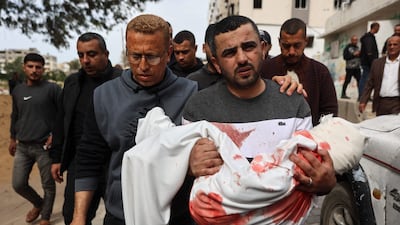 A relative carries a three-year-old girl ahead of her funeral in Gaza city. She was killed in an Israeli air strike. AFP