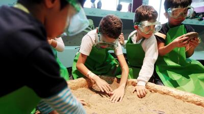 Children take part in the 'dig up a dinosaur' activity in the archaeology section of the Abu Dhabi Science Festival at Mushrif Central Park in Abu Dhabi. Christopher Pike / The National