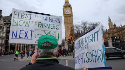 A man taking part in the farmers' protest at Westminster in London on March 25 holds placards outside Parliament. Reuters