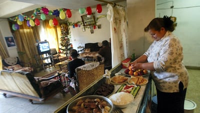 An Iraqi lady prepares a New Year's Eve meal in her kitchen as other family members watch television in the living room, at their home in an apartment block in the Al Sadun district of Baghdad, 31 December 2005. Ahmad Al-Rubaye / AFP