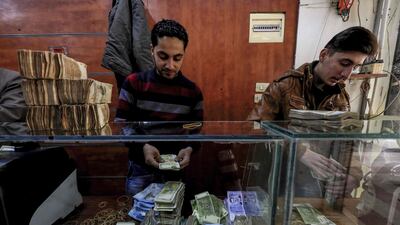 Employees of a currency exchange counter count banknotes at market street in the northeastern Syrian town of Qamishli. Delil souleiman / AFP