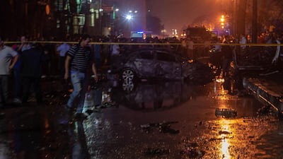 People surrounding a burned car after the explosion in downtown Cairo. AFP