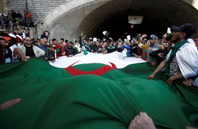 People carry a giant national flag as they protest over President Abdelaziz Bouteflika's decision to postpone elections and extend his fourth term in office. Reuters