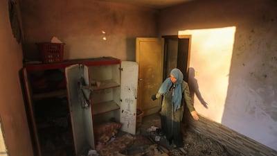 A Palestinian woman inspects the damage at her house after the strike. Mahmud Hams / AFP Photo.
