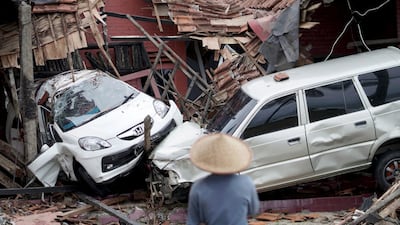 An Indonesian man looks at ruined vehicles. EPA