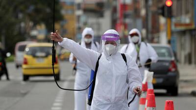Mary Luz Hernandez, 34, a professional seamstress, holds up her spray gun to offer passing cars her disinfecting service, amid the spread of the new coronavirus in Bogota, Colombia. AP Photo