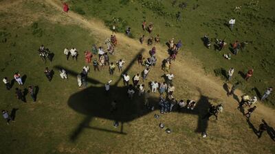 People wait for relief supplies being distributed by helicopter, near Allahabad. Rajesh Kumar Singh / AP Photo