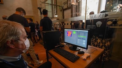 A man operates a temperature scanner as visitors arrive on the reopening day of the Uffizi museum, in Florence, Italy. AP Photo