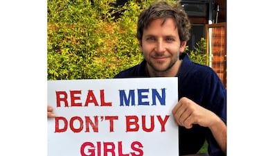 Bradley Cooper holds up a sign reading Real Men Don’t Buy Girls. Courtesy Bradley Cooper
