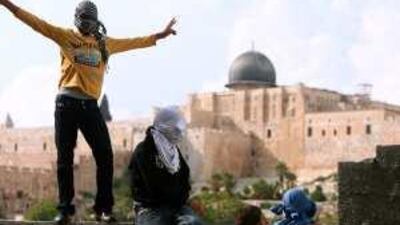 A Palestinian youth flashes the victory sign in an East Jerusalem neighbourhood yesterday. The al Aqsa mosque is seen in the background.