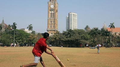 Residents of Mumbai play cricket as the Bombay Stock Exchange building is seen in the background (AP Photo/Rajesh Nirgude)