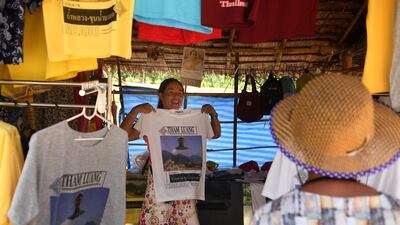 A visitor buying a souvenir T-shirt on the road leading to the Tham Luang cave. AFP