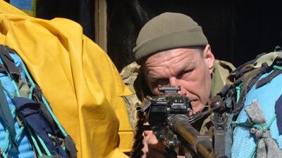A Ukrainian serviceman aims his weapon as he stands guard at a military checkpoint in Kharkiv. AFP