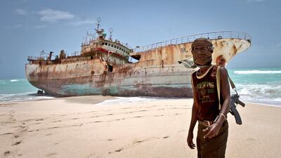 A masked Somalian pirate stands near a Taiwanese fishing vessel that washed ashore in Hobyo in 2012 after the pirates were paid a ransom and released the crew. Farah Abdi Warsameh / AP Photo
