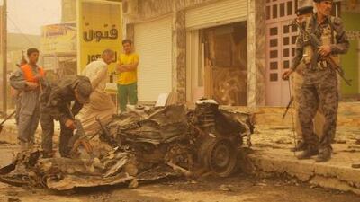 Enveloped by a sandstorm, Iraqis soliders inspect the debris following two car bombs in the western city of Ramadi, Iraq, today.