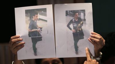 A Malaysian policewoman holds up pictures of the two men who boarded the missing Malaysia Airlines jet MH370 with stolen passports during a press conference on March 11, 2014, in Sepang, Malaysia. Wong Maye-E / AP Photo