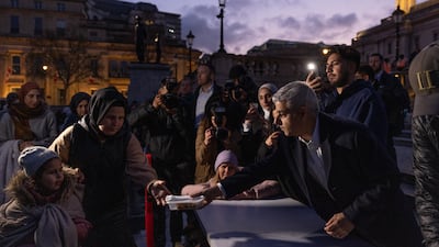 Mr Khan, right, hands out food for iftar in Trafalgar Square. Getty