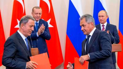Russia's Defense Minister Sergei Shoigu exchanges documents with Turkish counterpart Hulusi Akar, left, as their presidents applaud. AFP