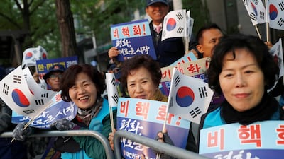 Supporters hold South Korean flags and signs while waiting for a convoy transporting South Korean President Moon Jae-in to the Korean summit.