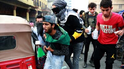 Iraqi protesters help their fellow protestor, who was affected by tear gas which was dispensed by riot police during clashes following a protest at Al Rasheed street in central Baghdad. EPA