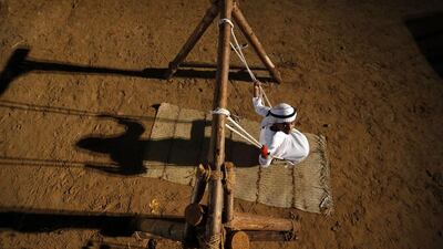 A young Emirati rides on a wooden swing. Karim Sahib / AFP Photo