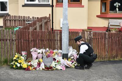 A police officer looks at flowers left in tribute to journalist Lyra McKee near the scene of her shooting. Getty