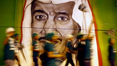 People walk in front of graffiti showing Saudi King Salman in Riyadh. The kingdom's 2Q non-oil economy grew at fastest rate since 2015. Ap