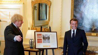 British Prime Minister Boris Johnson and French President Emmanuel Macron pose as they look at documents and artifacts related to former French President Charles de Gaulle during a visit at Downing Street in London. Reuters