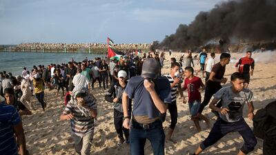 Palestinian protesters run for cover from teargas fired by Israeli troops during a protest on the beach at the border with Israel near Beit Lahiya, northern Gaza Strip. AP