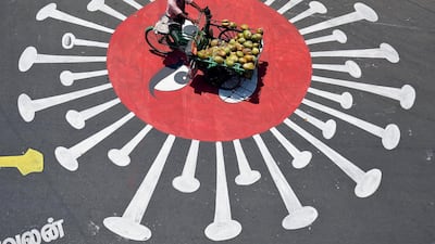 A man selling coconuts rides his trishaw across graffiti depicting the coronavirus in Chennai, India. Reuters