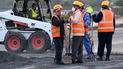 Laborers wearing protective face masks work on a street in Kuwait City. EPA