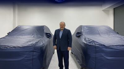 Mustafa Varank, Minister of Industry and Technology, poses with Turkey's new electric car, set to be unveiled on Friday. Courtesy: Turkish Ministry of Industry and Technology Twitter