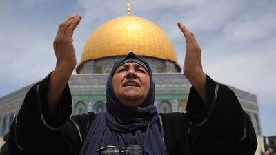 A Palestinian woman prays, with the Dome of the Rock shrine in the background. AP Photo