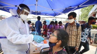 A girl undergoes a swab test at a bus stop in Bangalore, India, on April 7, 2021. EPA