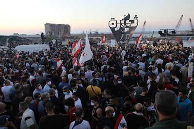 People wave Lebanese flags and chant to mark the one-year anniversary of anti-government protests with a background of the destroyed silos on the seaport on October 17, 2020 in Beirut, Lebanon. Getty Images