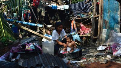 A woman bathes her child next to their destroyed house in Carcar, Cebu province. AFP
